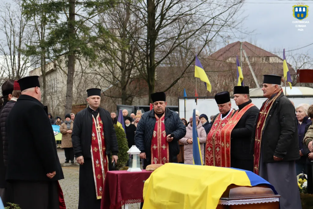 Священники проводять поминальну церемонію з українським прапором