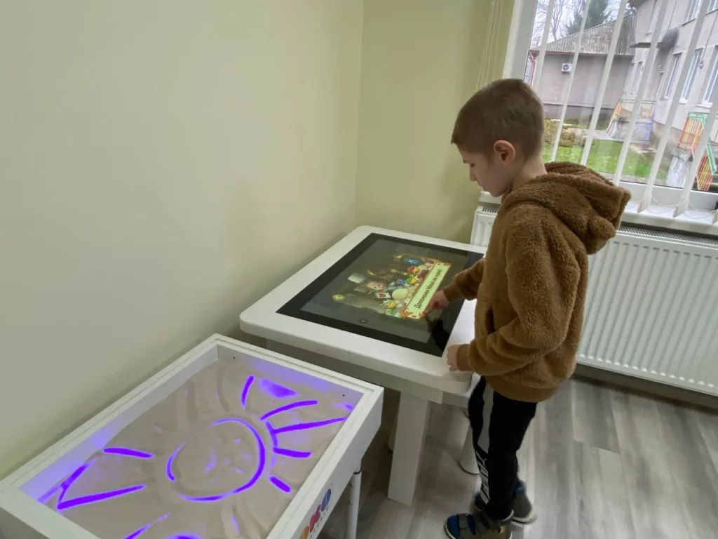 Дитина грає на сенсорному екрані в кімнаті