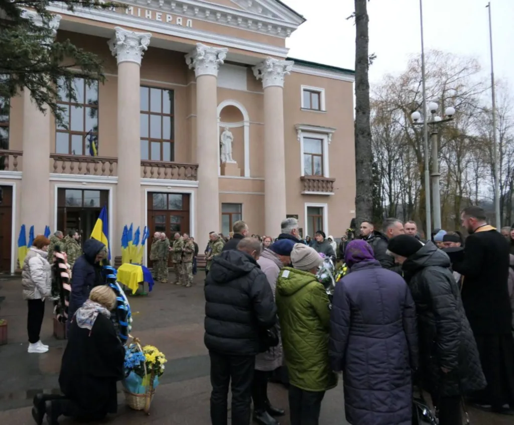 Люди вшанували військових біля будівлі з прапорами України