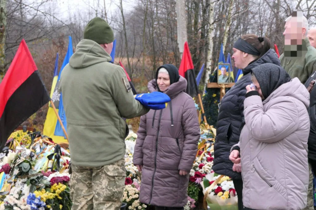 Прощання з військовим, люди біля могили з квітами