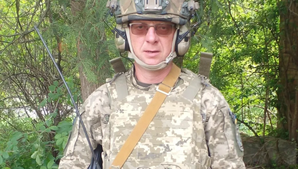 Військовий у камуфляжі стоїть серед дерев