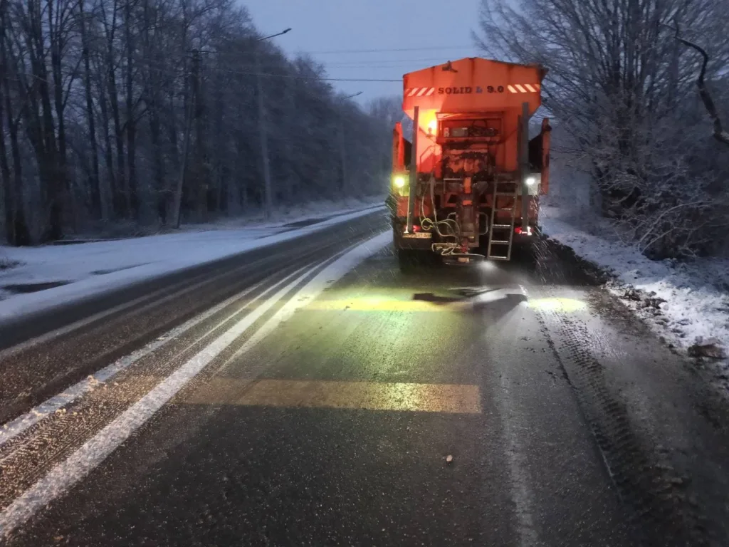 Снігоочисна машина посипає зимову дорогу