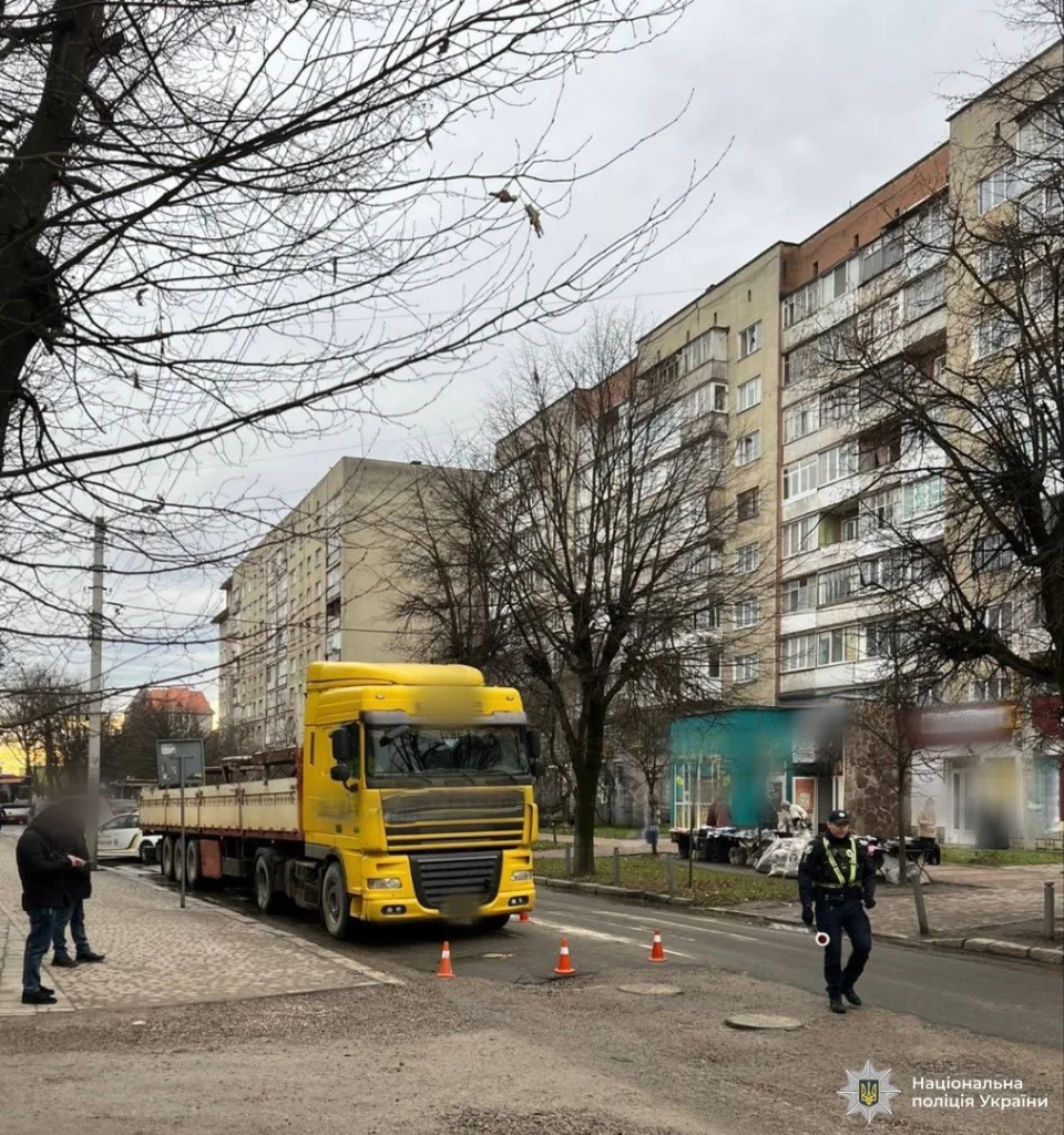 Поліцейський біля жовтої вантажівки на міській вулиці