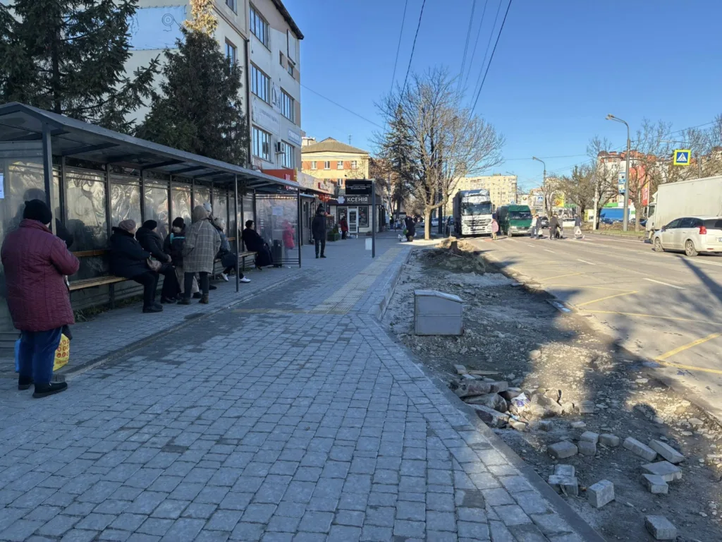 Люди чекають на автобус на міській зупинці