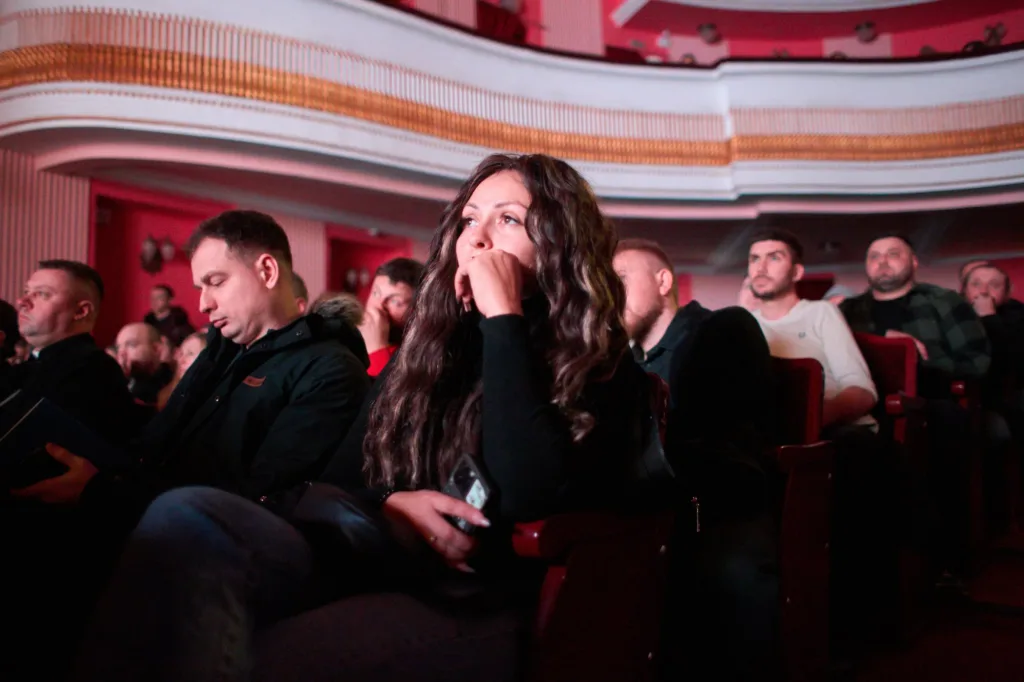 Люди уважно слухають подію в театрі