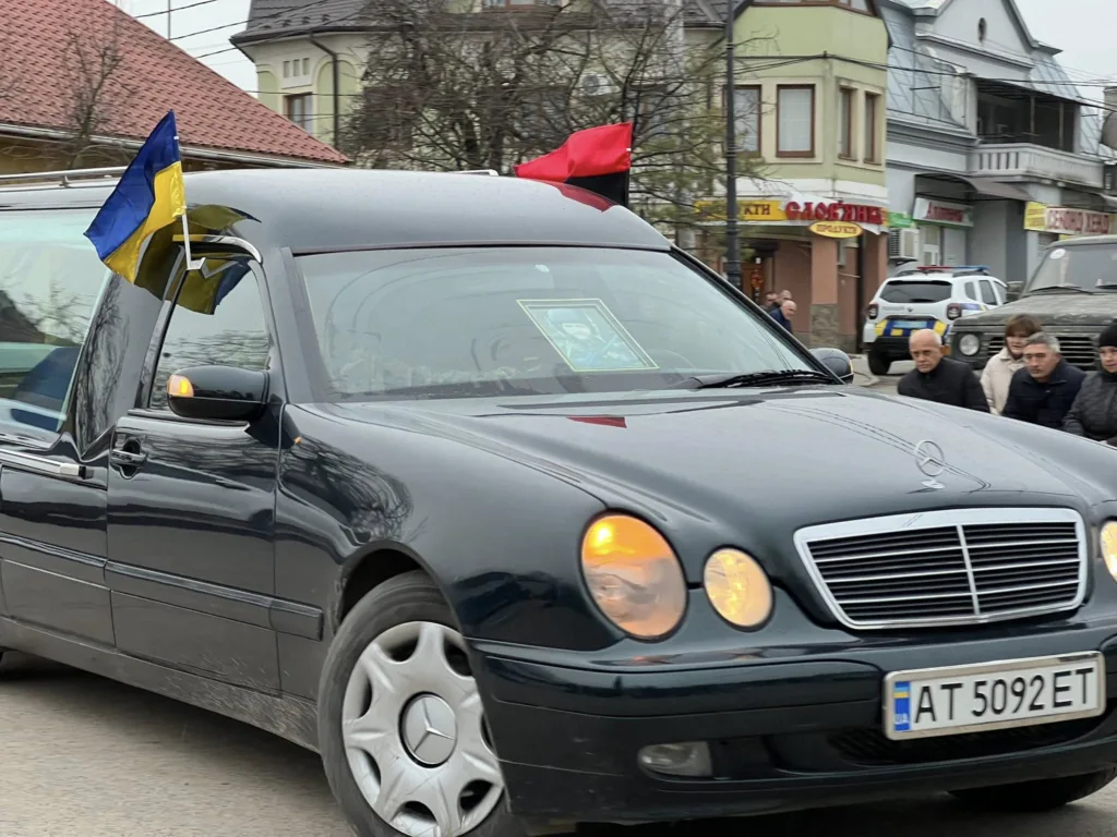 Катафалк з українським прапором на міській вулиці