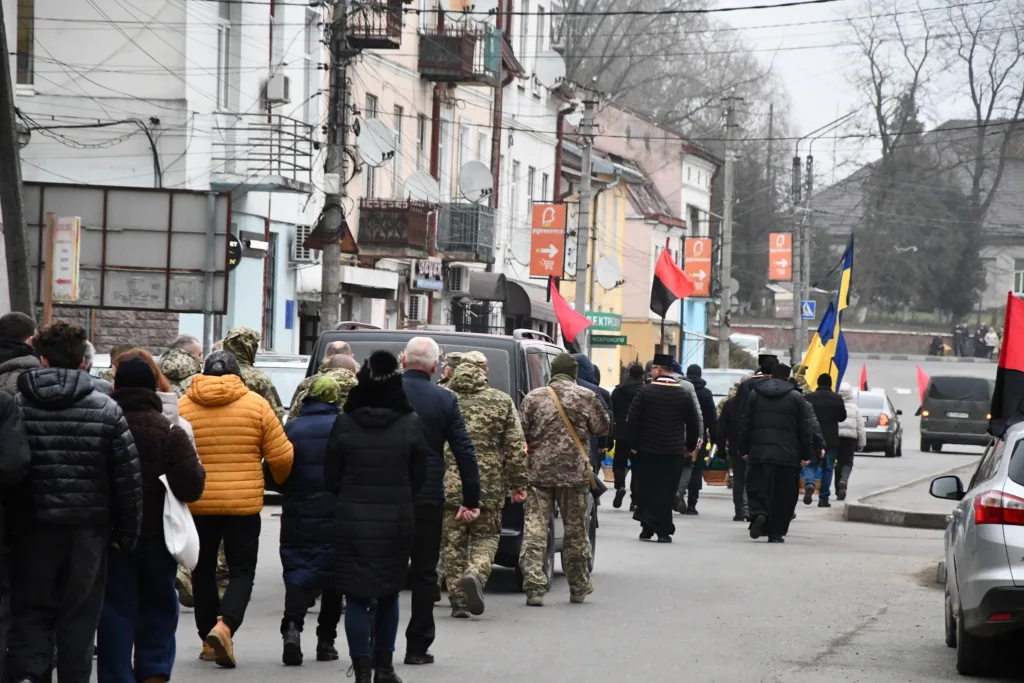 Люди йдуть вулицею з українськими прапорами