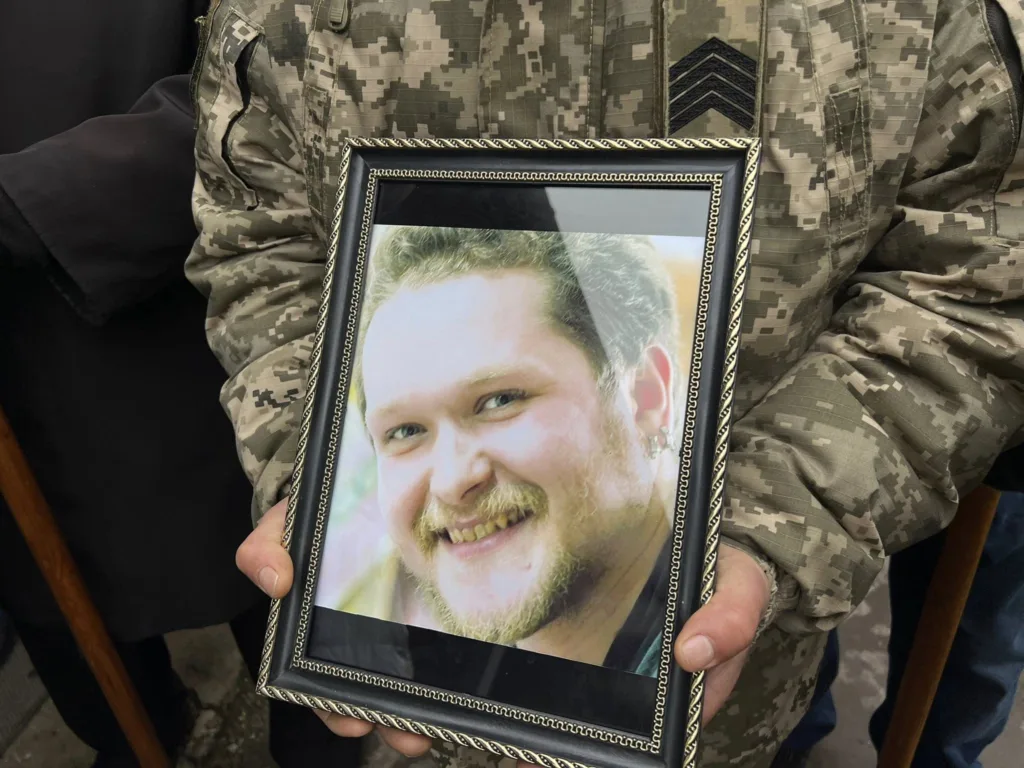 Військовий тримає фотографію чоловіка в рамці