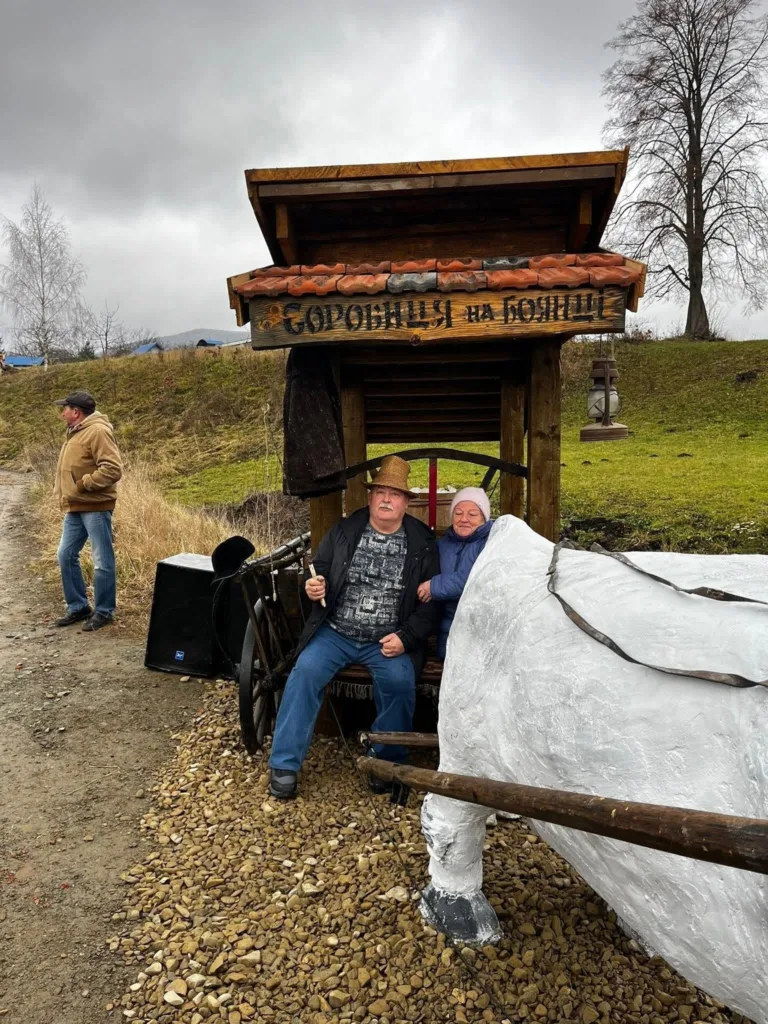 Люди в дерев'яному возі біля скульптури коня