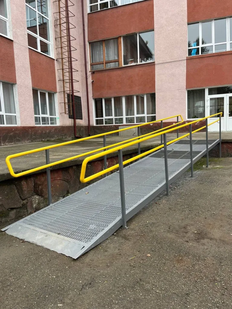 Пандус з жовтими поручнями біля шкільної будівлі
