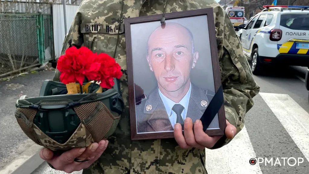 Військовий тримає фото загиблого героя та квіти