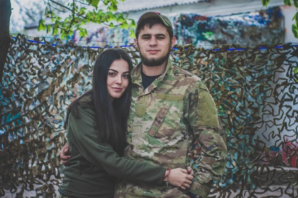 Пара обіймається перед маскувальною сіткою