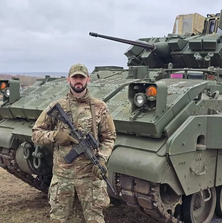 Військовий у камуфляжі стоїть біля бойової машини