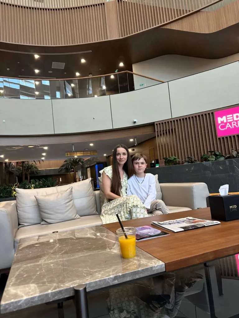 Жінка і хлопчик сидять у сучасному лобі клініки