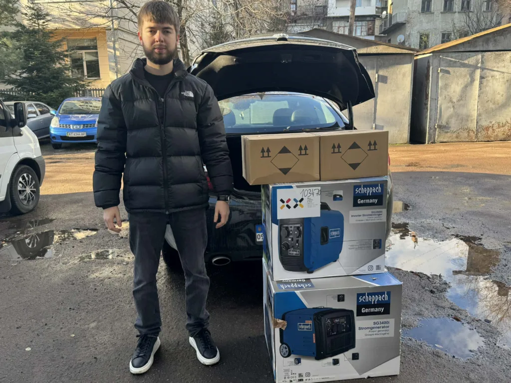 Чоловік поруч із коробками та генераторами біля авто
