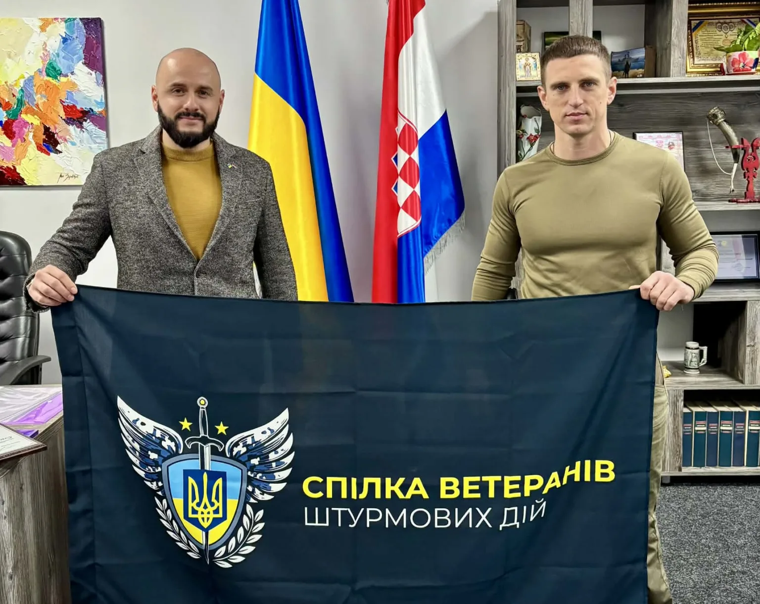 Двоє чоловіків тримають прапор Спілки ветеранів