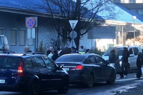 Люди переходять дорогу біля припаркованих автомобілів