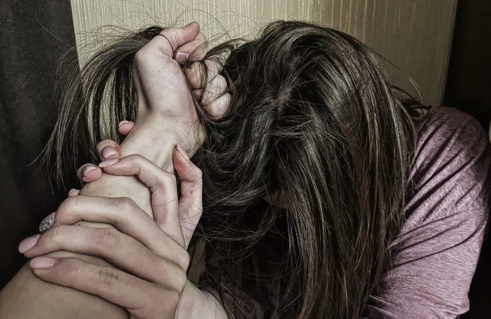 Жінка потерпає від насильства, хтось тримає її руку