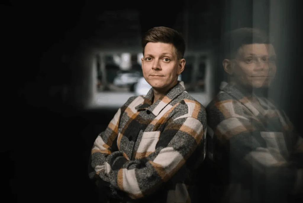 Людина в картатій куртці стоїть біля стіни