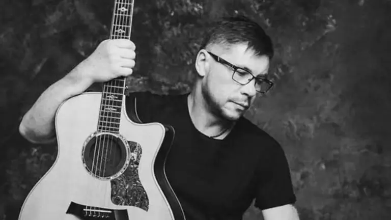 Чоловік з гітарою у чорній футболці