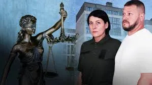 Двоє людей перед статуєю правосуддя