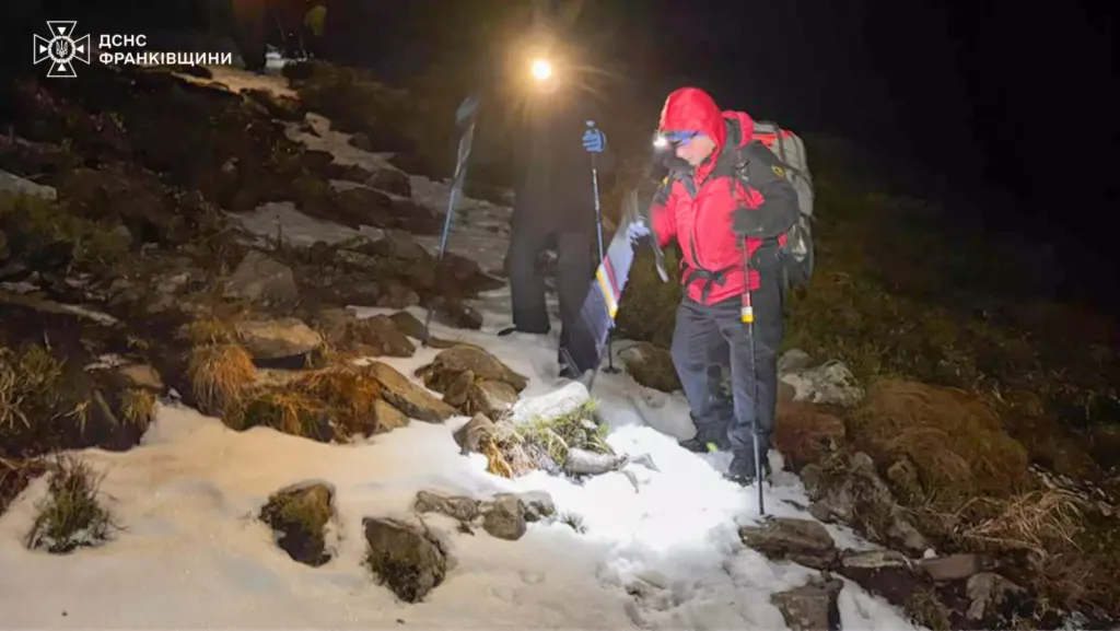 Рятувальники йдуть засніженою стежкою в горах уночі