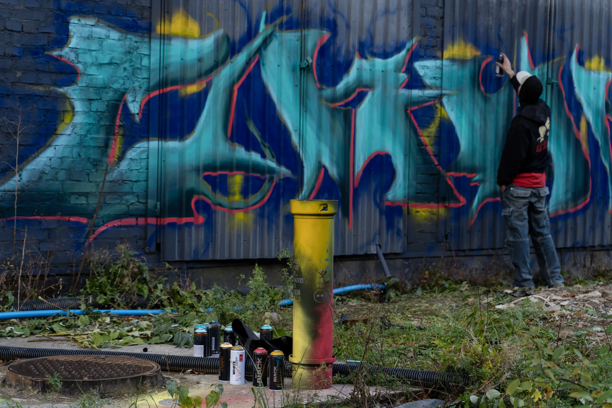 Художник малює графіті на стіні спреєм