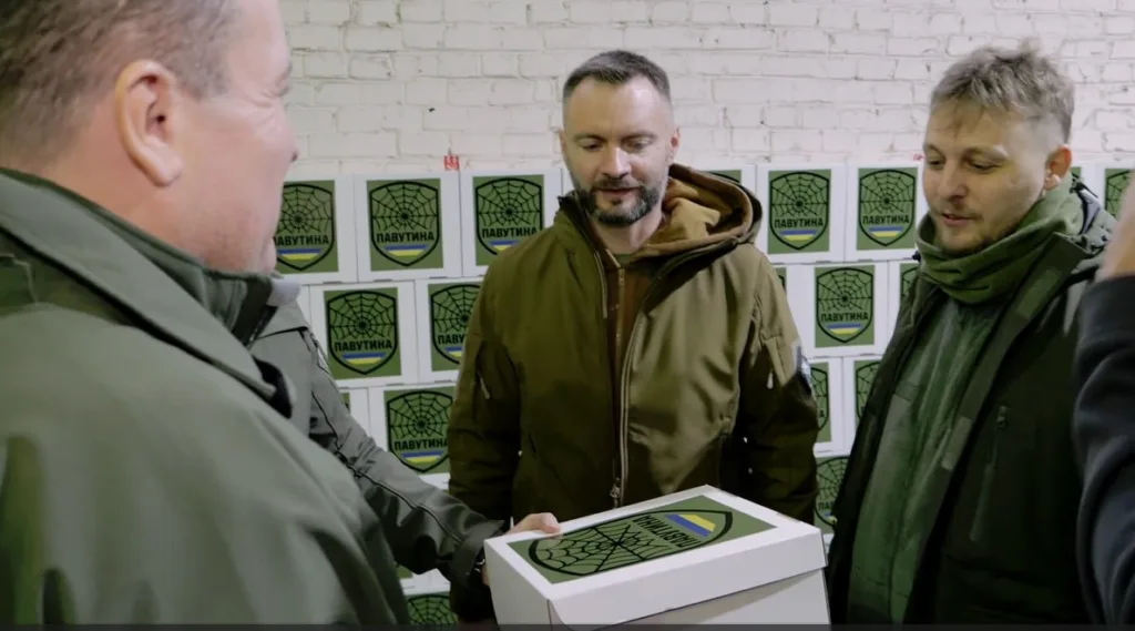 Люди тримають коробку з логотипом Павутина