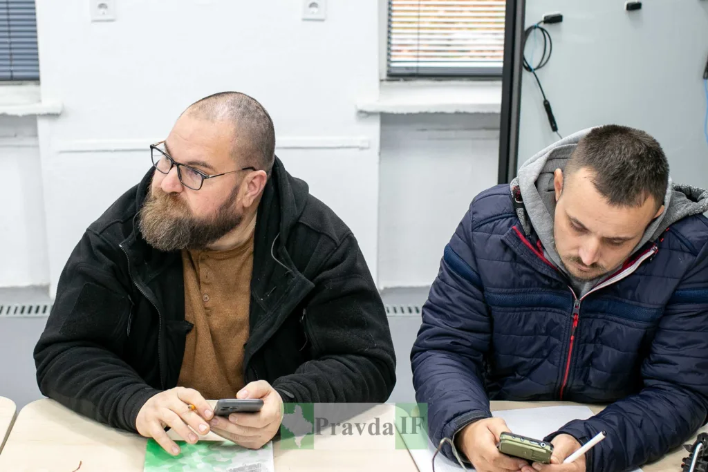 Двоє чоловіків працюють зі смартфонами за столом