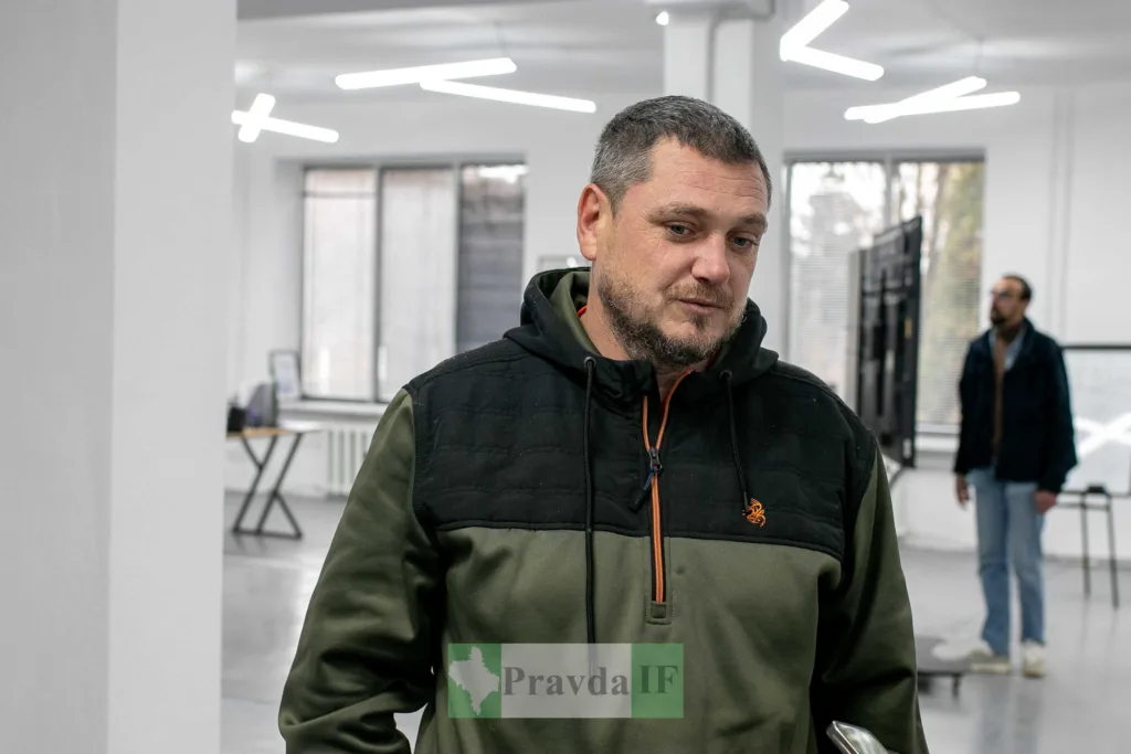 Чоловік у зелено-чорній худі в сучасному офісі