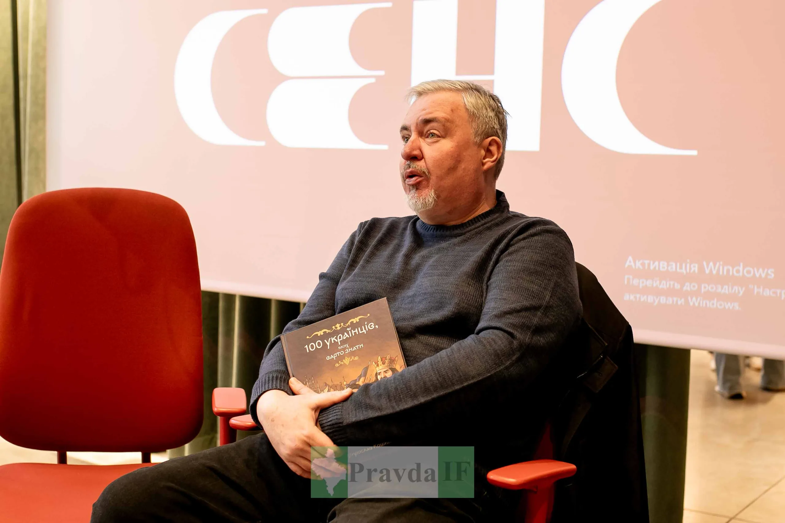 Чоловік з книгою на презентації у залі