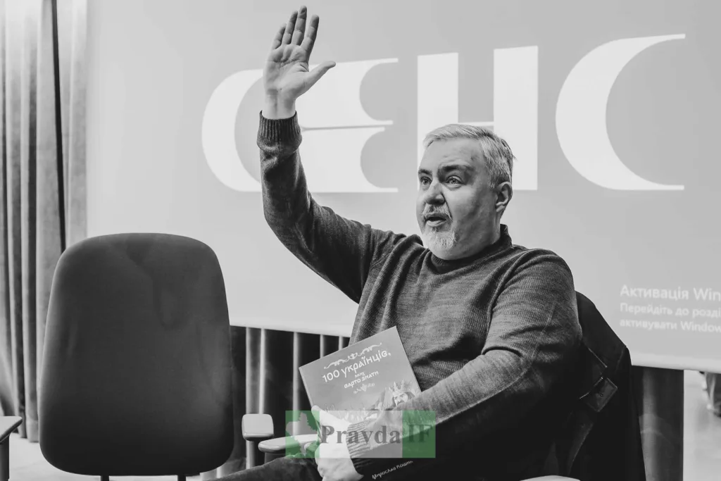 Чоловік піднімає руку під час презентації книги