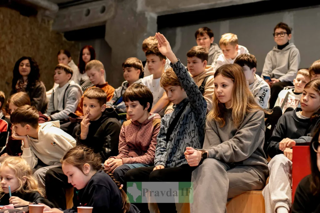 Учні на уроці, один піднімає руку