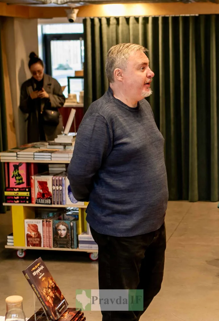 Чоловік виступає у книгарні перед полицями книг