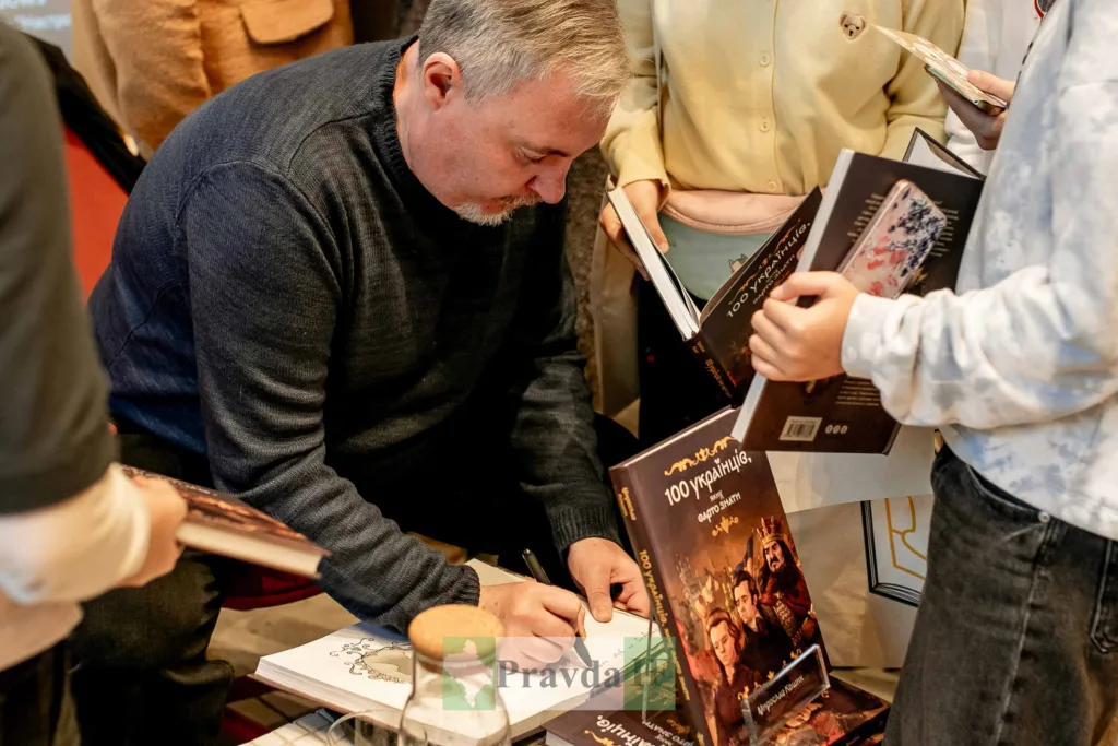 Автор підписує книгу на зустрічі з читачами