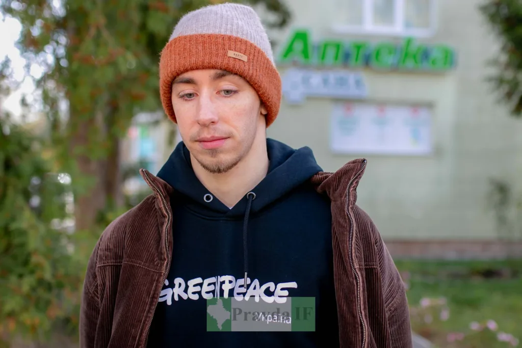 Молодий чоловік у шапці перед аптекою