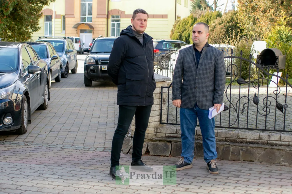 Двоє чоловіків стоять на вулиці біля паркану