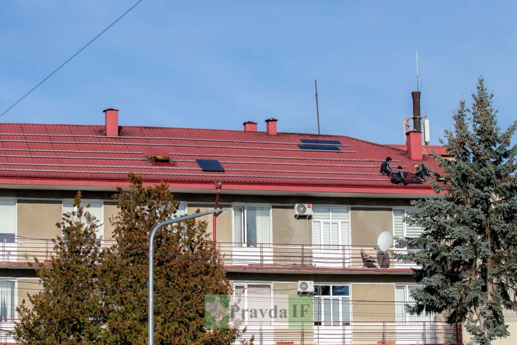 Робітники встановлюють сонячні панелі на даху будинку