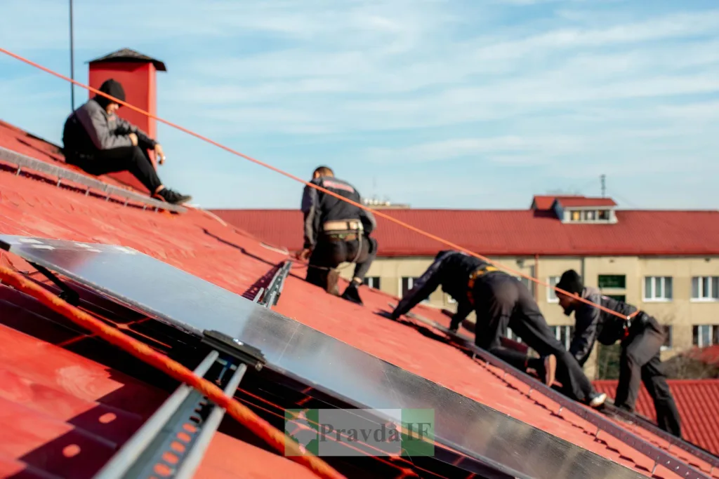Робітники встановлюють сонячні панелі на даху