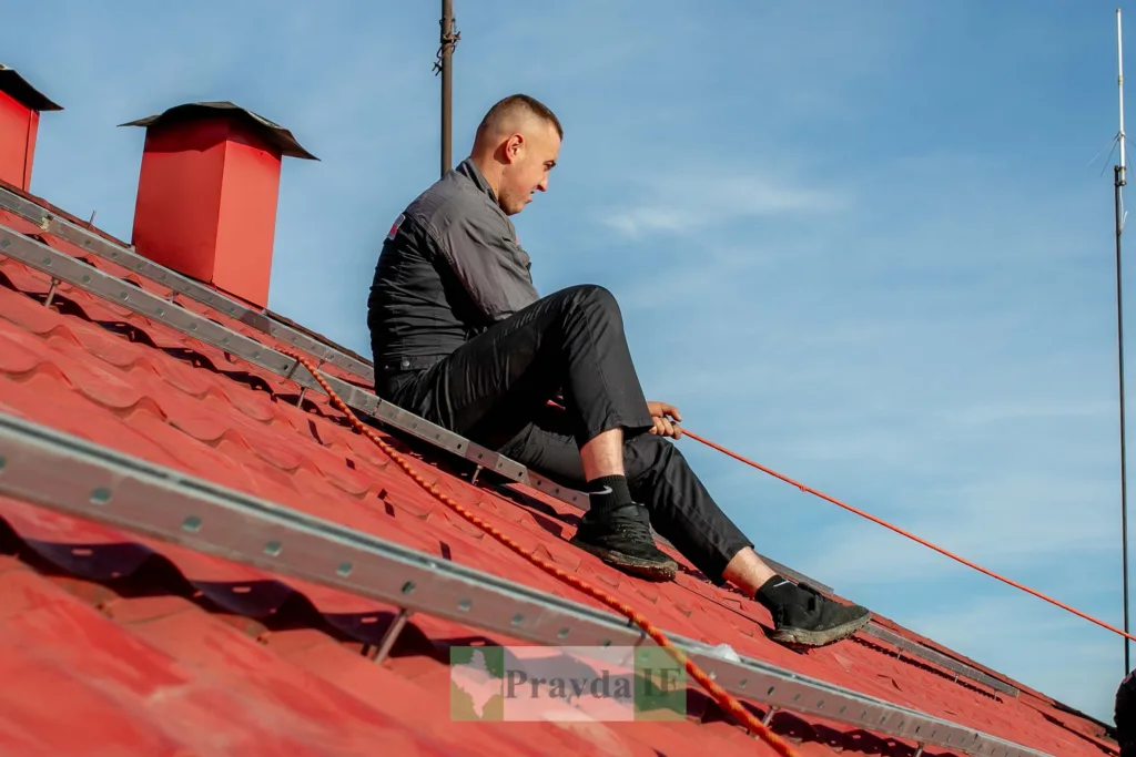 Робітник ремонтує червоний дах будинку