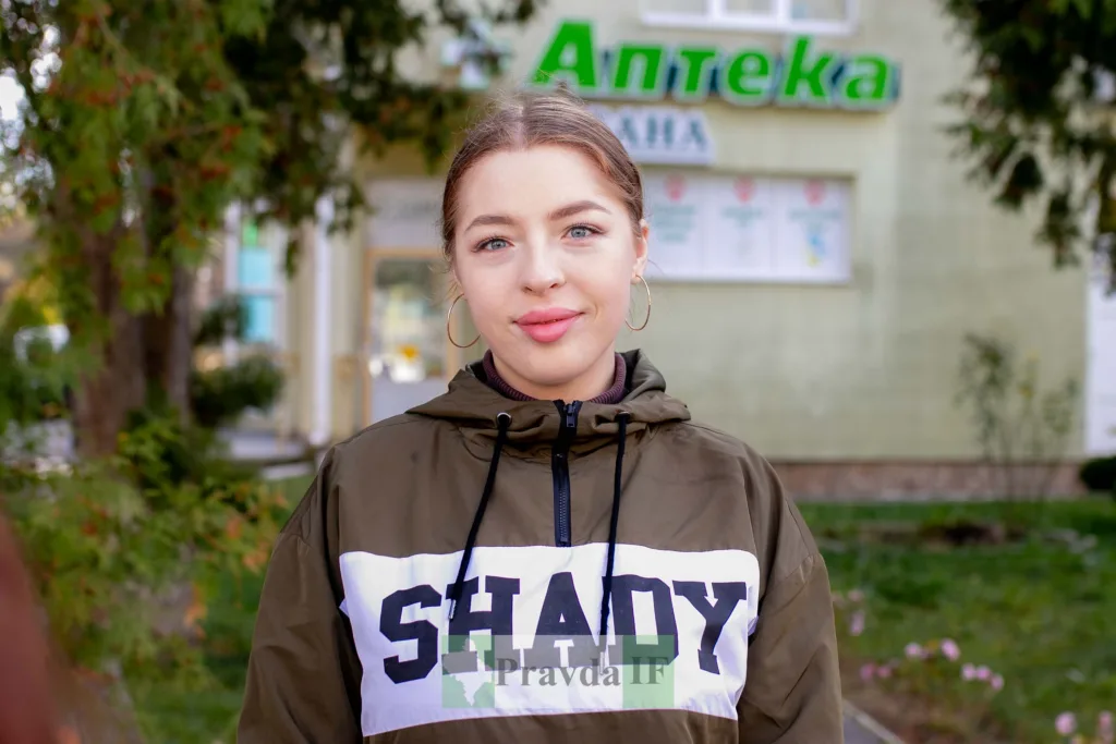 Жінка стоїть перед аптекою на вулиці