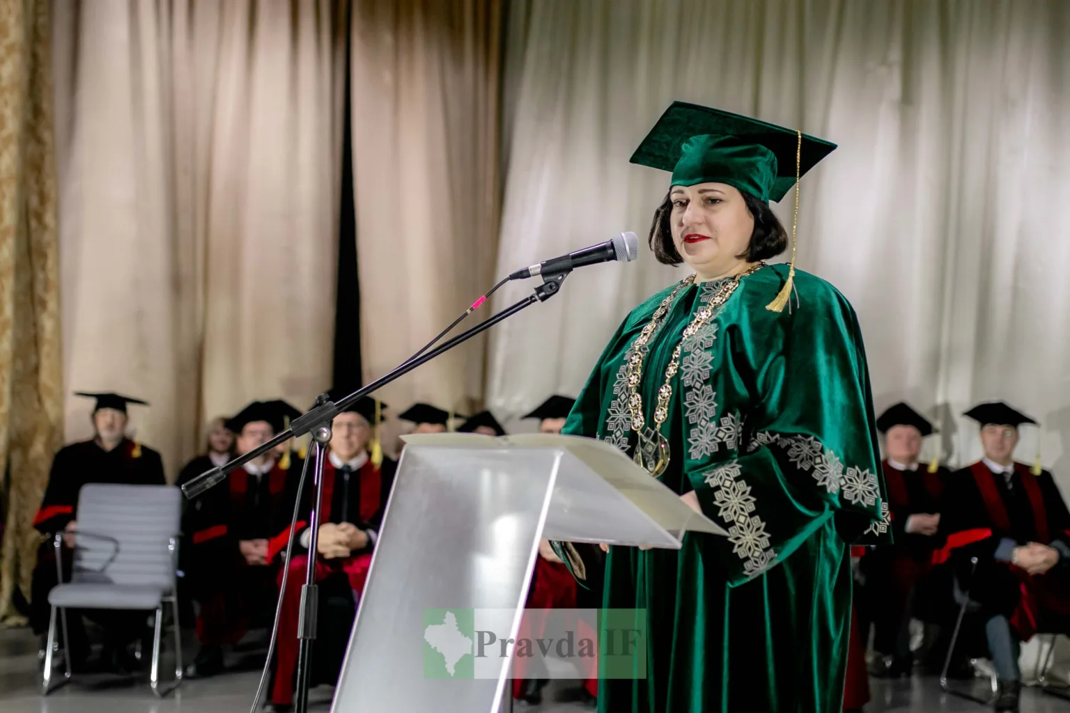 Жінка в академічній мантії говорить на сцені