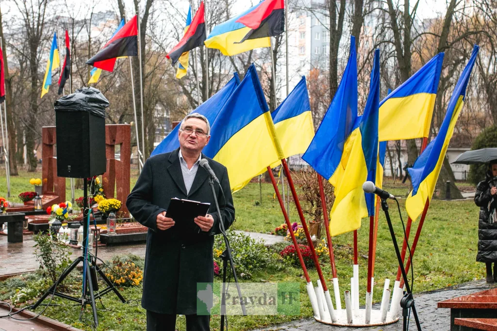 Чоловік виступає біля українських прапорів на заході