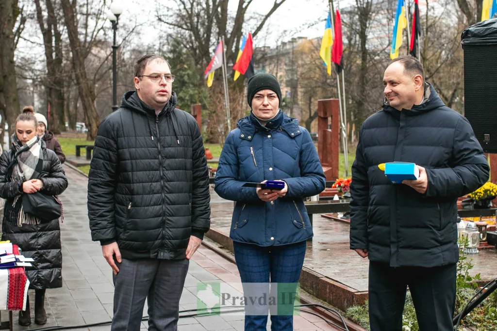 Люди на вшануванні з українськими прапорами