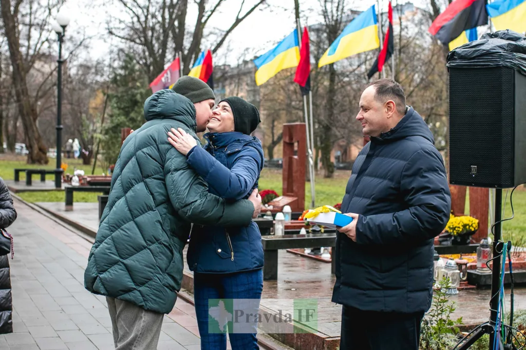 Люди вітаються на урочистому заході з прапорами України