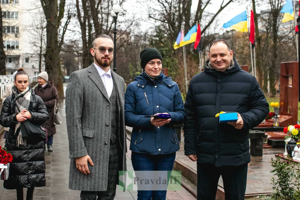 Люди на вшануванні з українськими прапорами