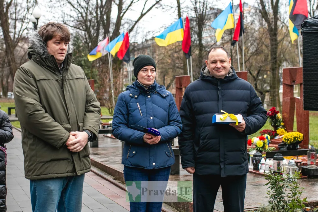 Люди на церемонії вшанування з українськими прапорами