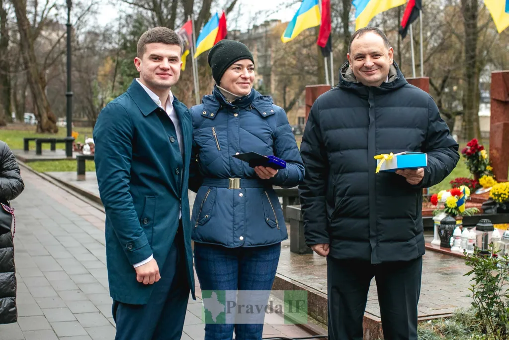 Люди на вшануванні з українськими прапорами