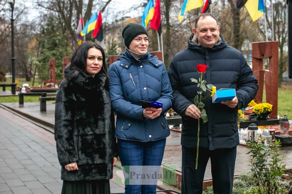 Люди вшановують героїв на меморіалі з прапорами