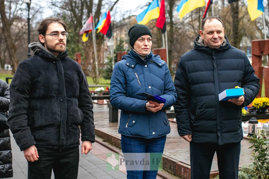 Люди на церемонії з українськими прапорами